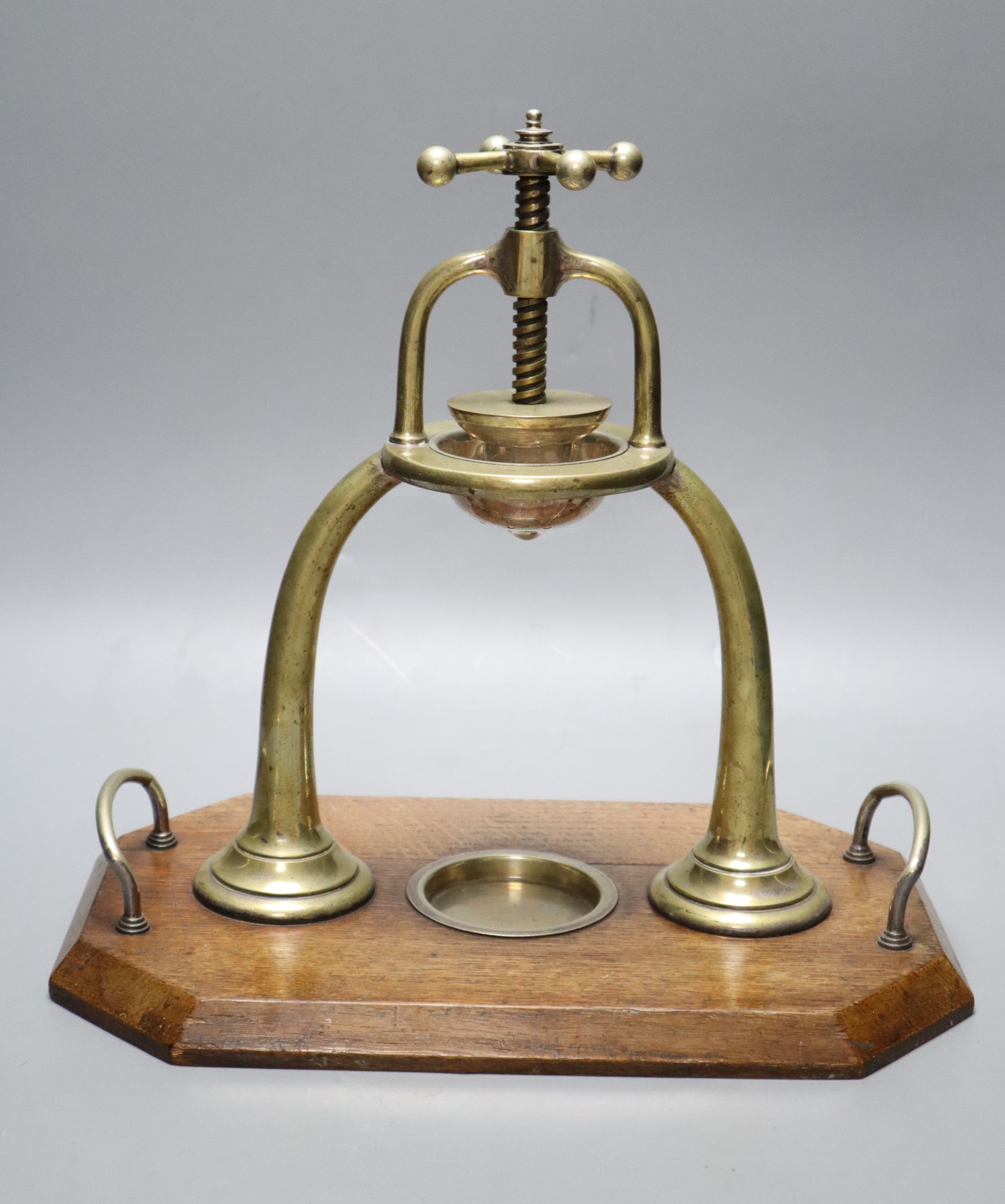 An Edwardian brass lemon squeezer on an oak plinth